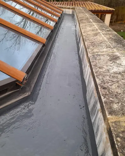 Box gutter beside a glazed roof, lined with a new grey GRP coating next to a stone parapet
